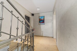 A hallway with a metal staircase, a poster of Amsterdam, and a plain wall. - Massira Social Living (Saâda)