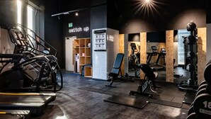 Ett gym med konditionsmaskiner, styrketräningsutrustning och en skylt med texten ”variera träningen”.