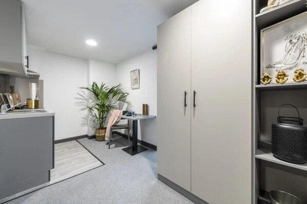 Une cuisine moderne avec un coin repas, une plante en pot et une étagère ornée d’objets décoratifs.