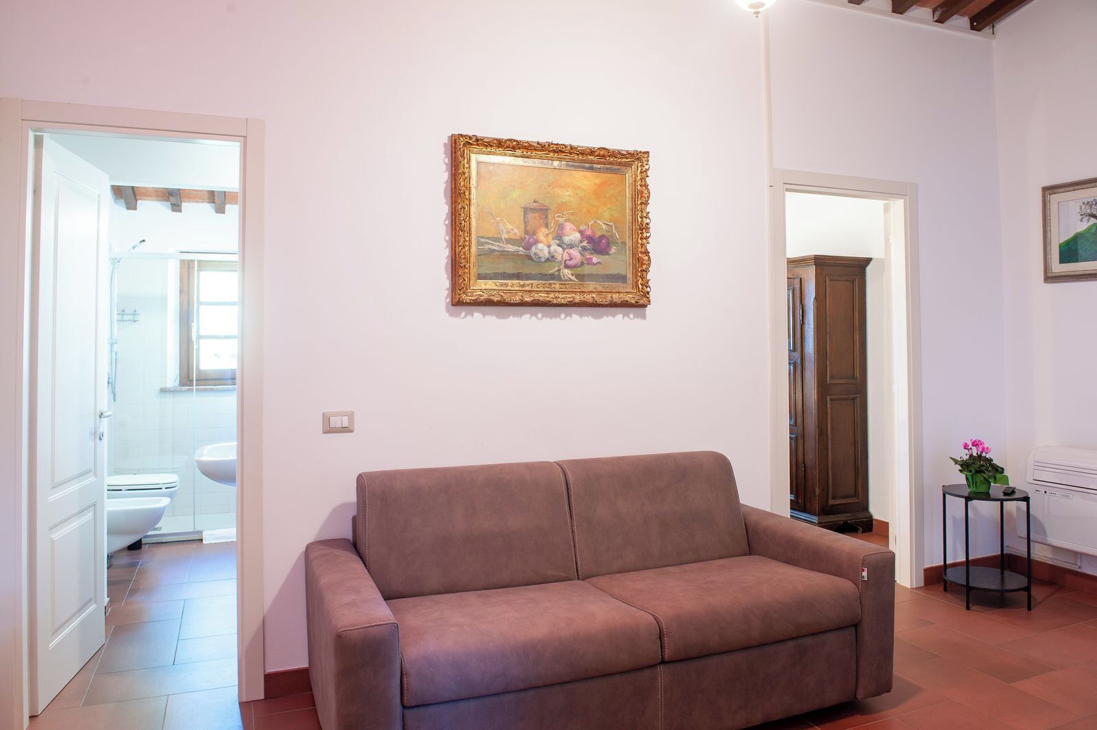 Ein Wohnzimmer mit einem braunen Sofa, einem Bild an der Wand und einer Holzkabine.