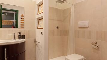 Een badkamer met een wastafel, toilet, douche en handdoekhouder.