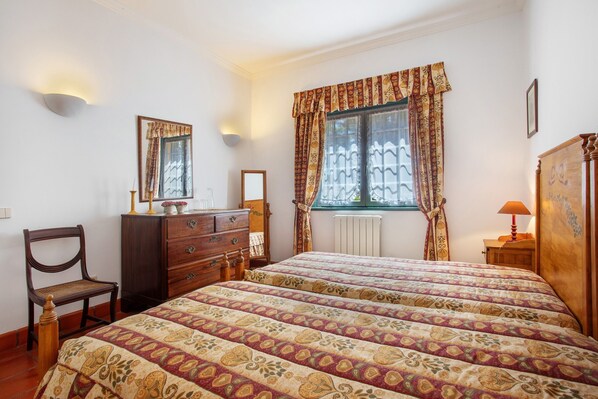 Un dormitorio con dos camas, un aparador, una silla, un espejo y una ventana con cortinas.