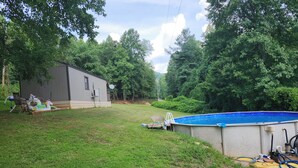 Un patio trasero con piscina, un cobertizo pequeño y césped.