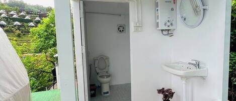 A small, enclosed bathroom with a toilet, sink, and a heater mounted on the wall.