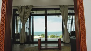 Una stanza con vista sul mare, un ventilatore a soffitto e un tavolo rotondo in legno.