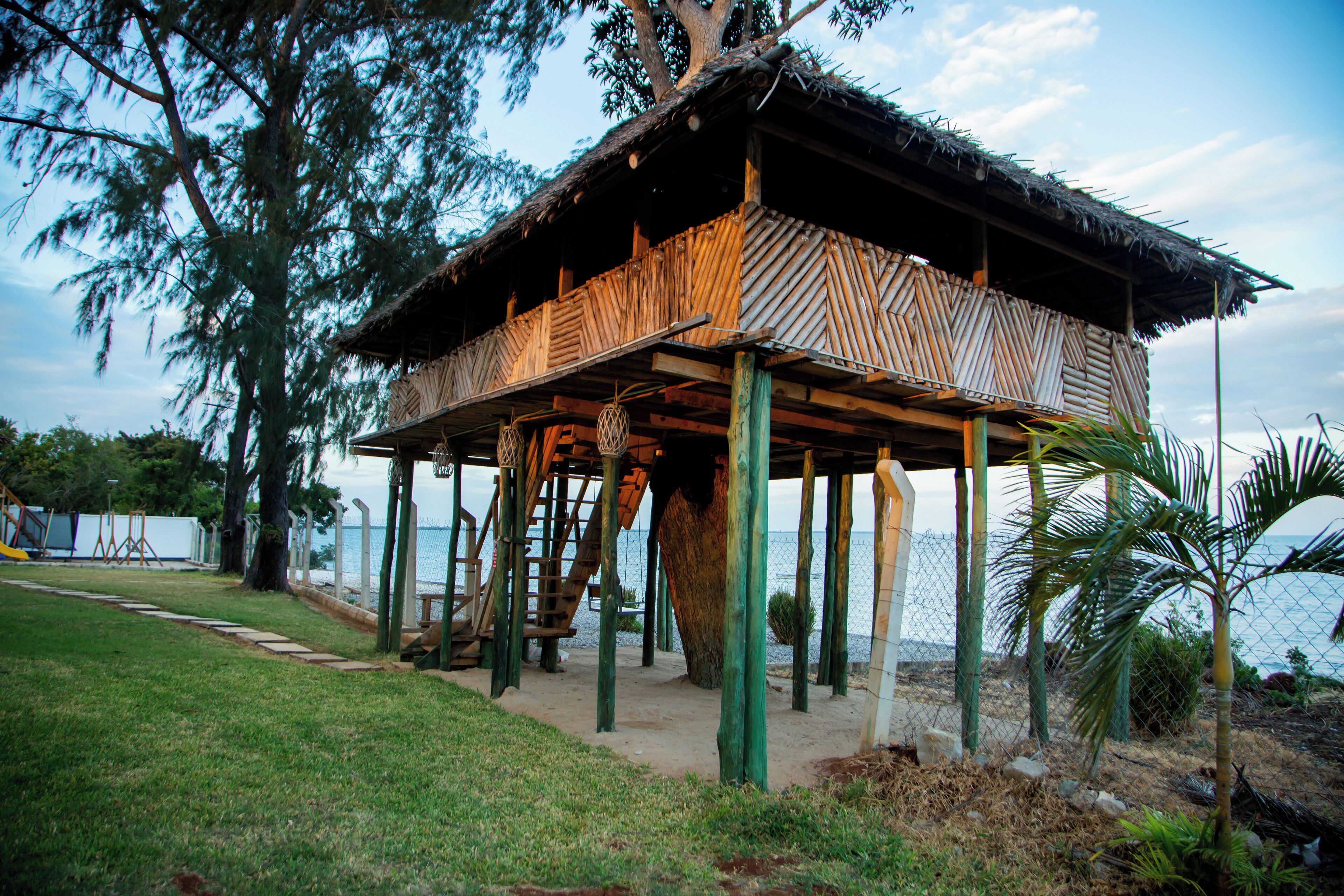A wooden structure with a thatched roof, supported by stilts, near a body of water.