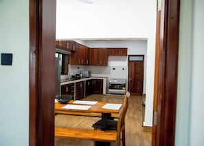 A kitchen with wooden cabinets, a stove, and a dining area with a table and chairs.