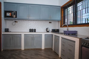 A kitchen with grey cabinets, a microwave, a kettle, and a toaster.