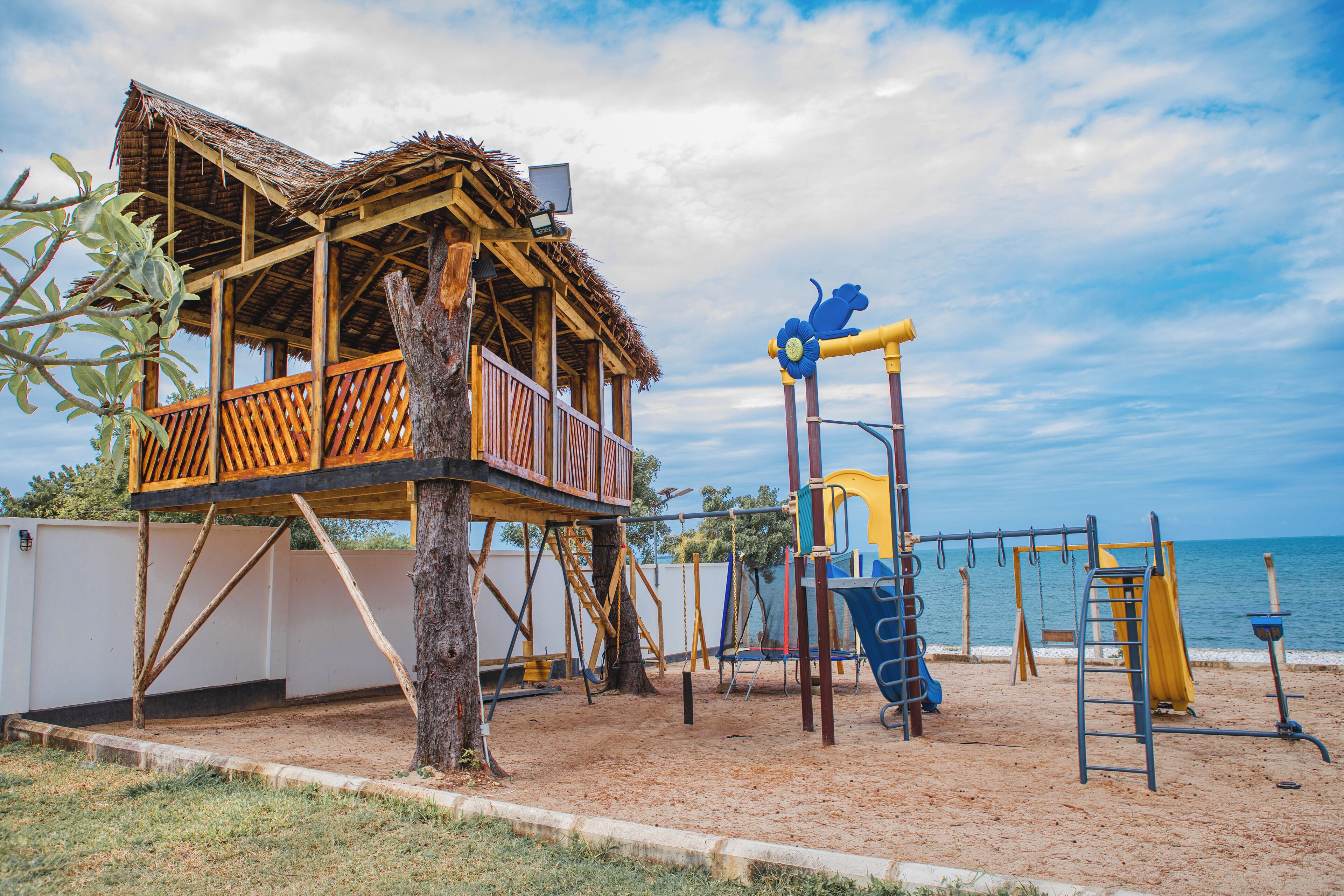 Une aire de jeux de plage avec une cabane en bois et des balançoires.