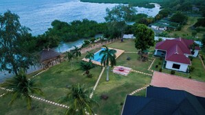 Vista aerea di una zona residenziale con piscina, una struttura con tetto di paglia e case dai tetti rossi.