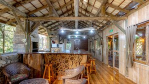 Un interno rustico in legno con un'area bar, mobili in vimini e una parete in pietra.
