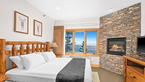 Un dormitorio con cama, chimenea de piedra y ventana con vistas a árboles.