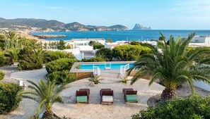 Un espace piscine avec des chaises longues, une terrasse en bois et une vue sur la mer et les montagnes.