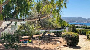 Un jardín con una hamaca, un columpio y vista al mar.