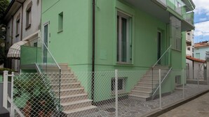 Un bâtiment écologique doté d’un balcon, d’un escalier et d’une zone délimitée par une clôture.