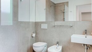 Une salle de bain moderne avec une douche à parois de verre, un bidet et un lavabo.