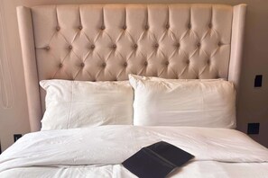A bed with a tufted headboard, two pillows, and a black book on the bed.