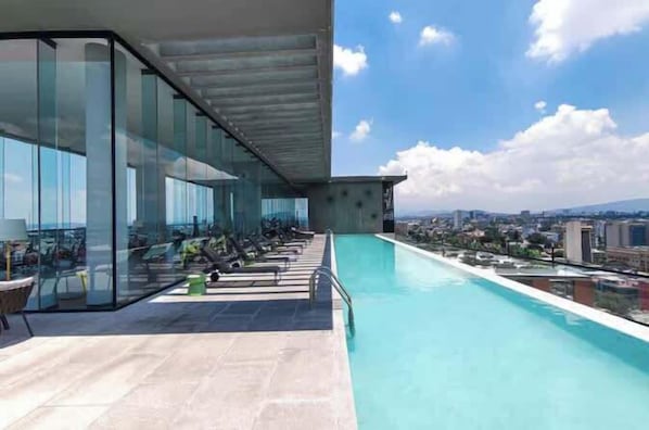 A rooftop pool with glass walls, a clear view of the city, and a modern architectural design.