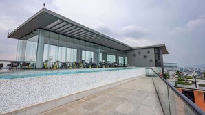 A modern building with a glass facade, a rooftop pool, and outdoor exercise equipment.