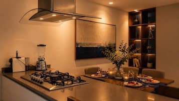 Une cuisine moderne équipée d’une cuisinière à gaz, d’un mixeur et d’un coin repas avec une table mise pour deux personnes.