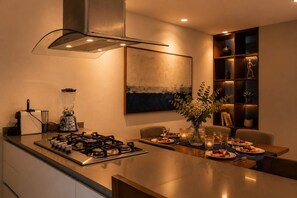 A modern kitchen with a gas stove, a blender, and a dining area with a table set for two.
