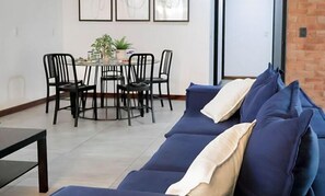 Relax in this stylish living room with a sofa, dining area, and brick accent wall.