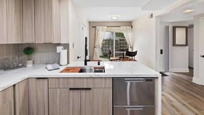 A modern kitchen with wooden cabinets, a stainless steel dishwasher, and a marble countertop. - Coronado On The Strand, Bay or Beach (Coronado)