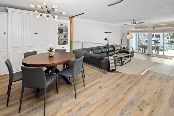 Un salon spacieux comprenant un coin repas, un canapé en cuir noir et une table à manger en bois.