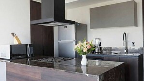 A modern kitchen with a central island, stainless steel appliances, and a vase of flowers.