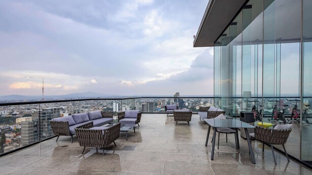 A rooftop terrace with seating and exercise bikes, offering a city view.
