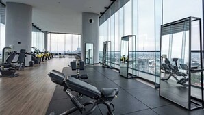 A gym with various exercise equipment, large windows, and a city view.
