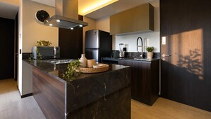 Uma cozinha moderna com ilha central, eletrodomésticos embutidos e acabamento em madeira escura.