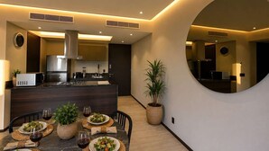 Uma cozinha moderna com uma ilha central, mesa de jantar posta com pratos e copos, e um espelho grande na parede.