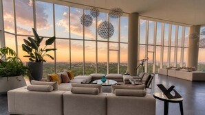 A spacious living room with a large sectional sofa, a coffee table, and a view of the cityscape through large windows.