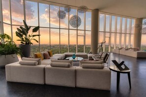 A spacious living room with a large sectional sofa, a coffee table, and a view of the cityscape through large windows.