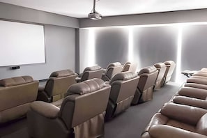 Una sala de cine en casa moderna con asientos reclinables de cuero y una gran pantalla de proyección.