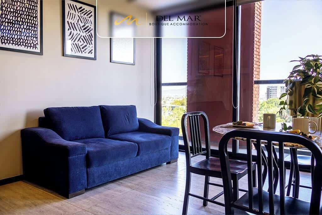 Ein modernes Wohnzimmer mit einem blauen Sofa, einem Esstisch mit Stühlen und Bildern an den Wänden.