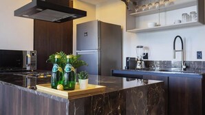 Uma cozinha moderna com ilha de mármore, eletrodomésticos de aço inoxidável e máquina de lavar louça embutida.