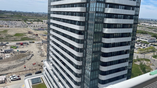 A high-rise building with multiple balconies and a view of a construction site in the foreground. - "Chic Retreat: Pet & Smoke-Friendly, Balcony Views, Prime Location!" (Vaughan)