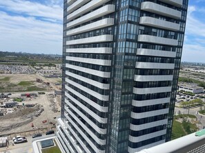 Een hoog gebouw met meerdere balkons en uitzicht op een bouwplaats op de voorgrond.