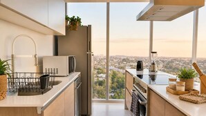 A modern kitchen with a view of a cityscape, equipped with a refrigerator, microwave, and stove.