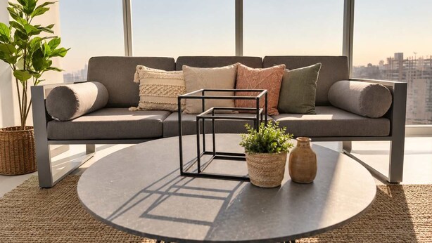 A modern living room with a sectional sofa, a round coffee table, and a city view.