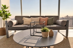 A modern living room with a sectional sofa, a round coffee table, and a city view.