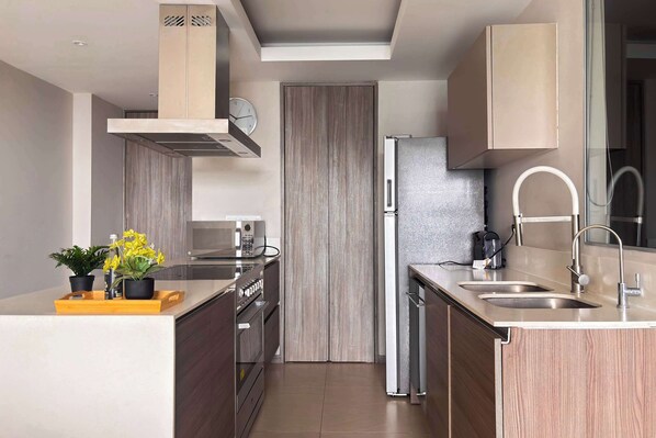 A modern kitchen with a built-in microwave, a stainless steel refrigerator, and a double sink.
