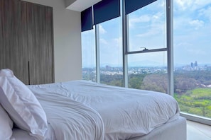 A bedroom with a large window, a bed, and a wardrobe. - 2BR Near Andares | Stunning City Views (Guadalajara)