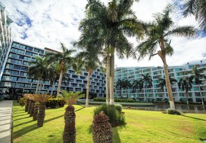 A modern hotel with a central courtyard, palm trees, and a water feature. - Stay by the Sea I Cozy Condo (Nuevo Vallarta)