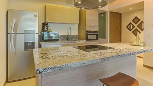 A modern kitchen with a granite countertop, stainless steel appliances, and a central island.