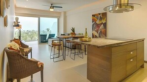 A modern kitchen with a central island, bar stools, and a dining area with a table and chairs.