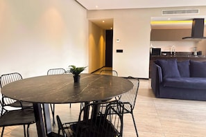 Un comedor moderno con una mesa redonda, sillas negras y una planta en maceta.
