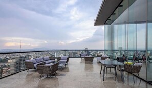 Une terrasse sur le toit, aménagée avec des sièges et des vélos d’exercice, offrant une vue sur la ville.